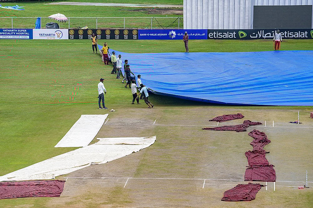 | Photo: PTI/Kamal Kishore : Afghanistan Vs New Zealand Test: Groundsmen remove the cover of the pitch before the start of second day match